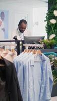 verticale video Al dettaglio assistente nel elegante moda boutique in attesa per ricevere lotto di nuovo merce, imputando dati su digitale dispositivo. lavoratore nel capi di abbigliamento memorizzare in attesa consegna di indumenti a partire dal