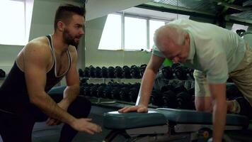 Trainer watching how senior client does exercises video