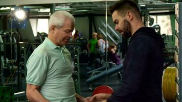 Trainer give barbell to the senior client video