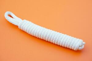 White rope, Keeping long rope to be shorter on orange background. Concept, practice to tie different pattern of rope to apply in daily life such as tying things or doing  activities. photo