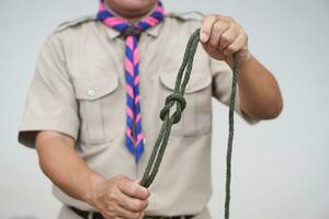 Tying rope knot pattern, demonstrated by scout teacher trainer. Concept, useful tying knot for many purposes in daily life. Tying knot rope teaching aid. Life skills with rope. photo