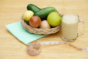 vaso de zalamero mezclado frutas, cesta de Fresco frutas y medición cinta. concepto, sano bebida para salud. bien siendo y peso pérdida menú. hecho en casa refrescante Fruta bebidas alto fibras, desintoxicación foto