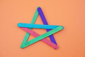 DIY colorful used ice cream sticks in star shape. Concept, teaching aids. Educational craft. Create kids imagination with colors and teaching materials about shapes photo