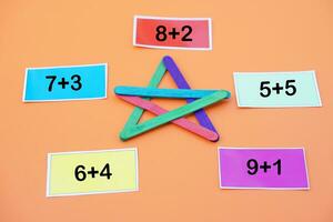 Paper cards with numbers addition, plus for teaching Maths subject. DIY colorful used ice cream sticks in star shape. Concept, teaching aids, Educational number game. photo