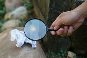 Close up hand hold magnifying glass to make fire for burning paper. Concept, Science experiment about convex lens, hold magnifying glass between the sun and tinder. Handy survival skills. photo