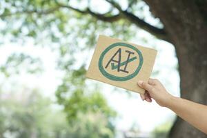 Close up hand holds paper card with  drawn sign AI in circle and tick mark. Concept, Choose ,agree and accept to use AI or Artificial Intelligence to apply in daily life. photo