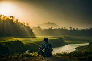 a man sits on the edge of a hill overlooking a river and the sun setting. AI-Generated photo