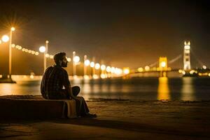 un hombre sentado en el playa a noche con el dorado portón puente en el antecedentes. generado por ai foto