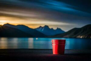 a red bucket sits on the ground in front of a lake. AI-Generated photo