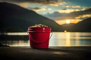 a red bucket with nuts sitting on the ground near a lake. AI-Generated photo