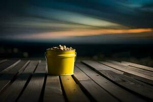 un amarillo Cubeta sentado en un de madera mesa con un puesta de sol en el antecedentes. generado por ai foto