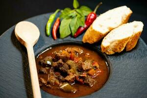 traditional Hungarian food beef goulash with bread an spicy peppers photo