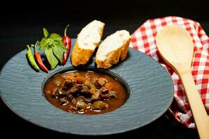 traditional Hungarian food beef goulash with bread an spicy peppers photo