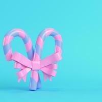 Pink christmas candy canes with a bow on bright blue background in pastel colors photo