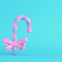 Pink christmas candy cane with a bow  on bright blue background in pastel colors photo