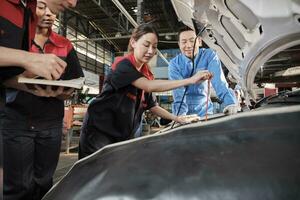 Asian male professional automotive supervisor advises and inspects a mechanic worker woman about liquid engine oil at car garage, service maintenance, and fix specialist occupations auto industry. photo