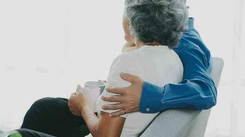 feliz Senior casal usando controlo remoto ao controle para mudança canal. idosos Assistir televisão para entretenimento enquanto homem usando controlo remoto ao controle. esposa e velho homem sentado em sofá dentro vivo quarto com televisão mostrar. video