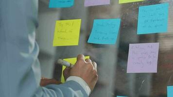 Young asian business woman working on project plan using sticky papers notes on glass wall, people meeting to share idea, Business design planning concepts. video