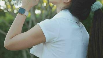 Young woman athlete takes a break, drinking water, out on a run on a hot day. video