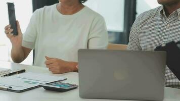 multi-etnisch groep van gelukkig bedrijf mensen werken samen, vergadering en brainstorming in kantoor gebruik makend van computer, laptop, tablet, en mobiel telefoon. video