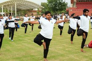 nuevo Delhi, India, junio 21, 2023 - grupo yoga ejercicio sesión para personas a yamuna Deportes complejo en Delhi en internacional yoga día, grande grupo de adultos asistiendo yoga clase en Grillo estadio foto