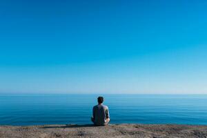 Desolate individual gazing out to sea isolated on a blue gradient background photo