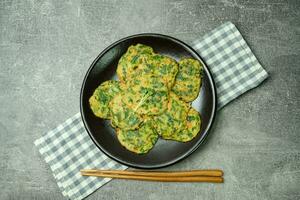 buchujeon, korean Chive Pancake, To prepare this dish, chive, julienned carrot, and green pepper are mixed with flour and pan-fried in a flat, round, pancake-like shape. photo