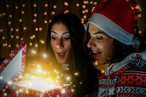 two cute young women are surprised opening the christmas present from the magic lights photo