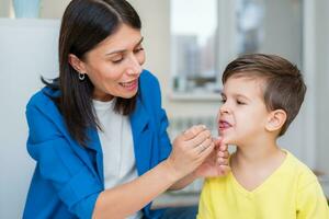 Woman speech therapist helps a boy correct the violation of his speech photo