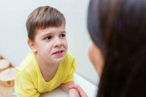 Woman speech therapist helps a boy correct the violation of his speech photo