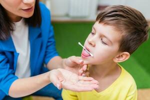 A woman speech therapist deals with the child and teaches him the correct pronunciation and competent speech. photo