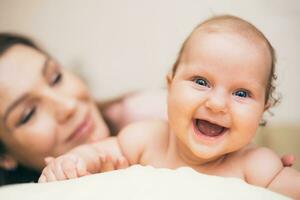 Happy laughing baby spending time with his mom in the apartment photo