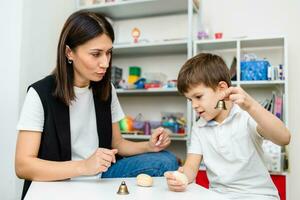 A woman speech therapist deals with the child and teaches him the correct pronunciation and competent speech. photo