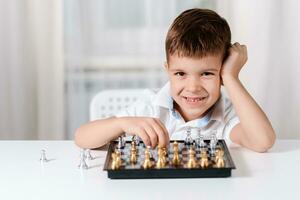 Laughing child playing chess at the table at home photo