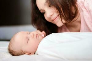 Young mother takes care of her baby in the bedroom photo