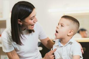 A woman speech therapist deals with the child and teaches him the correct pronunciation and competent speech. photo