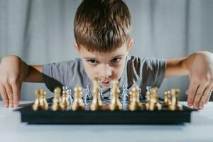 Child learns to play chess in his room at home photo