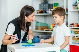 A woman speech therapist deals with the child and teaches him the correct pronunciation and competent speech. photo