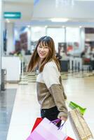 pretty happy young chinese woman with colorful shopping bags photo