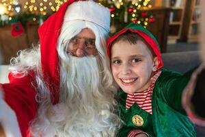 Papa Noel claus toma un selfie en Navidad noche juntos con un joven duende foto