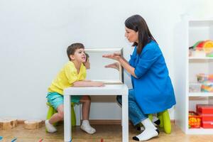 Cute boy in speech therapist office corrects his speech photo