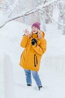 Smiling girl photographer taking pictures of snow in winter park photo