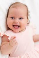 Cute happy baby lies on a white sheet and is covered with a woolen cloth photo