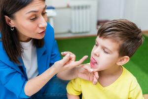 un mujer habla terapeuta ofertas con el niño y enseña él el correcto pronunciación y competente discurso. foto