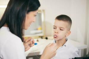 Woman speech therapist helps a boy correct the violation of his speech photo