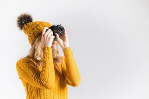 Portrait of a beautiful girl photographer in a knitted hat who takes pictures in the studio photo