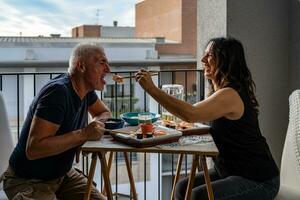 beautiful middle aged couple eating Chinese take away food sitting at a laid table photo