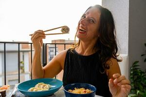 Attractive middle-aged woman eating Chinese take away food sitting at a laid table photo