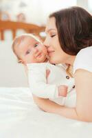 Portrait of a young woman kissing her little baby daughter photo