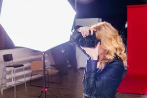 Portrait of a cute girl photographer taking pictures in a photo studio